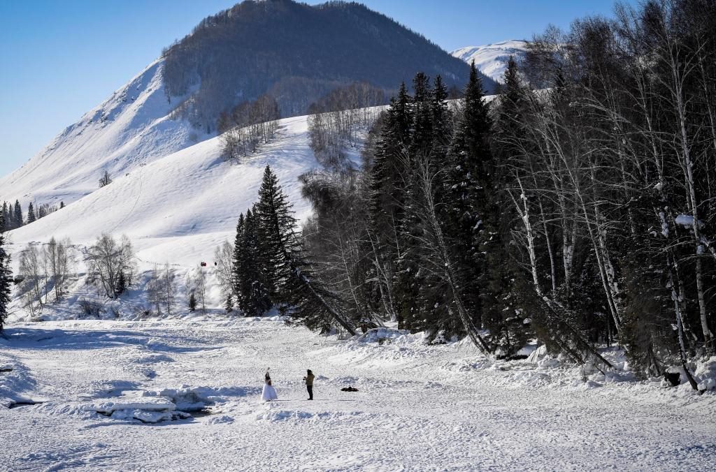 2024年2月5日，兩名游客在新疆阿勒泰地區(qū)布爾津縣禾木村拍照。新華社記者 馬鍇 攝