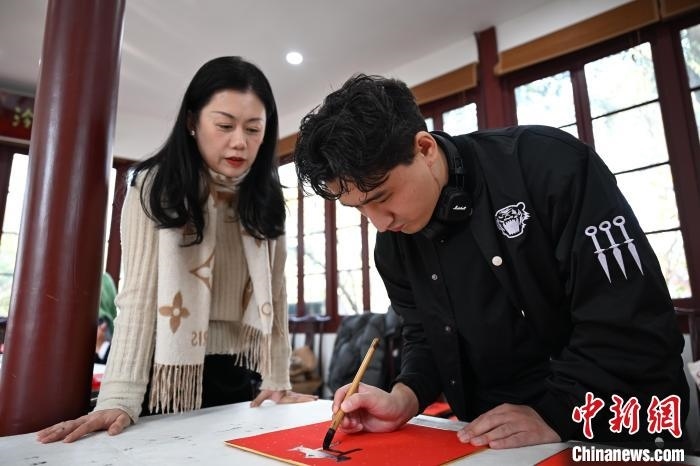 1月20日，外籍留學(xué)生在西泠印社社員李硯指導(dǎo)下寫福。當(dāng)日，來自巴西、馬來西亞、加納、哈薩克斯坦的外籍留學(xué)生在浙江杭州西泠印社體驗(yàn)福貼、春聯(lián)和篆刻，感受古老的中國傳統(tǒng)文化。中新社記者 王剛 攝