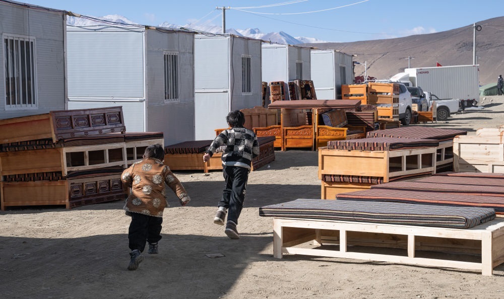 2025年1月13日，在定日縣嘎旦村，兩個(gè)孩子在剛運(yùn)來的兩排藏床間奔跑。新華社記者丁增尼達(dá) 攝