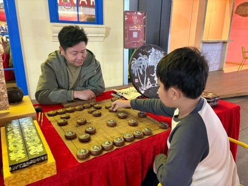 柯秋楓與市民下椰雕象棋。人民網(wǎng) 陳葉欣攝