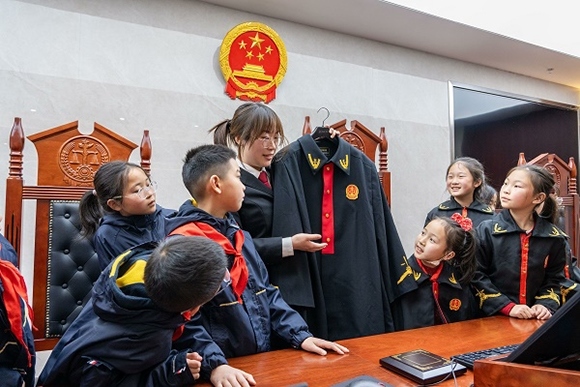 圖②：干警向同學(xué)們介紹法袍。