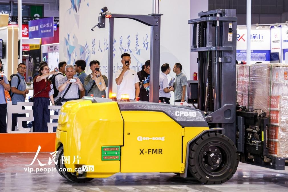 第24屆中國工博會現(xiàn)場，觀眾觀看叉取機器人作業(yè)演示。王初攝（人民圖片網(wǎng)）