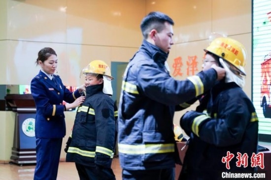 圖為學生們現(xiàn)場穿戴消防頭盔和戰(zhàn)斗服。中新社記者 趙宇航 攝