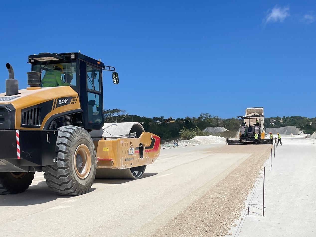 圖為中企承建的牙買加蒙特哥貝繞城路項(xiàng)目基層試驗(yàn)段正在進(jìn)行攤鋪和碾壓施工，相關(guān)施工工作已于日前順利完成。中國(guó)港灣美洲區(qū)域公司供圖