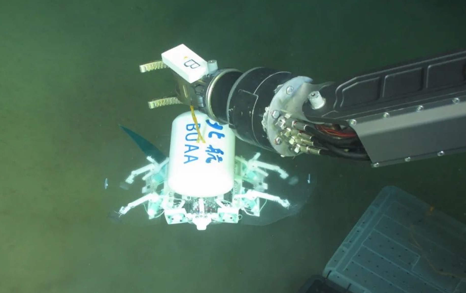 科研人員利用機械臂將北航深海小型機器人投于馬里亞納海溝。校方供圖