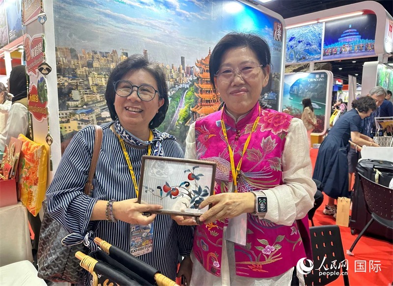 中國(guó)“大冶刺繡”傳承人劉小紅（右）參加泰國(guó)國(guó)際旅游展，向觀眾介紹中國(guó)非遺刺繡針?lè)?。人民網(wǎng)記者 簡(jiǎn)承淵攝