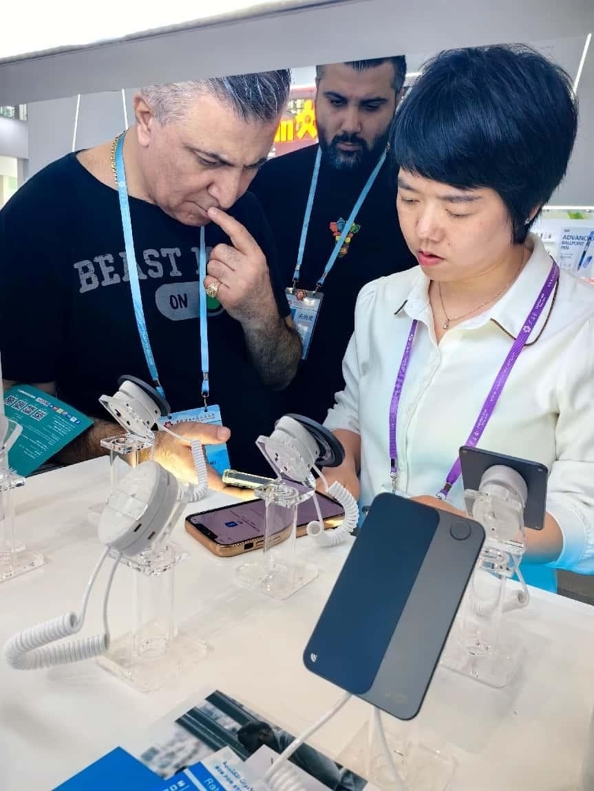 展臺工作人員向外商展示“AI TOP翻譯終端”。圖片來源：受訪者提供