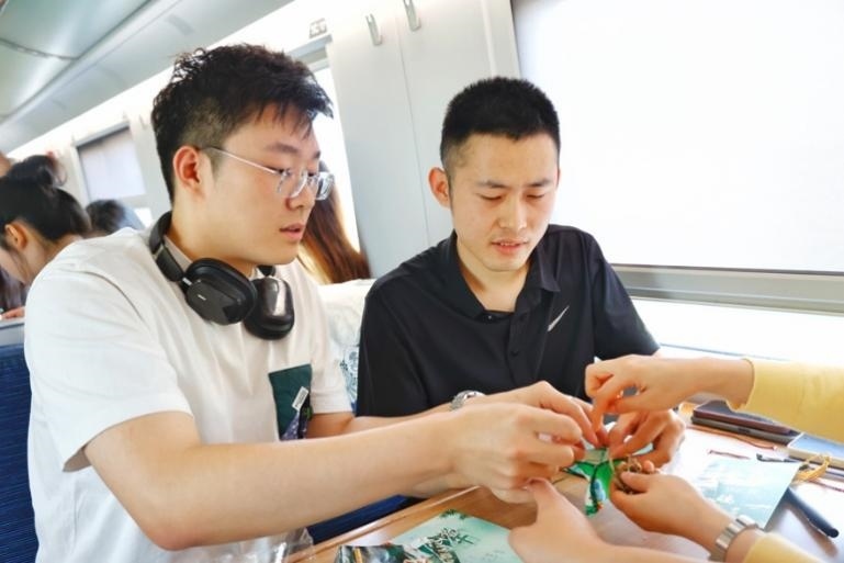 G232次旅客親手制作端午荷包和五彩繩。王磊攝